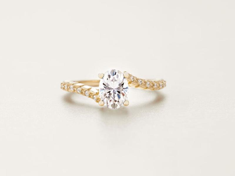 Oval diamond engagement ring on a twisted pavé band in yellow gold
