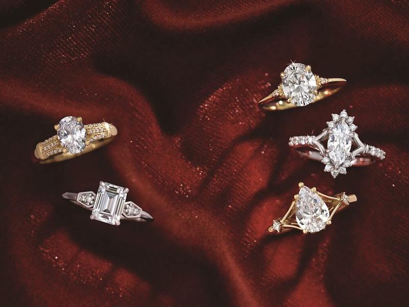 Five custom diamond engagement ring settings on red satin