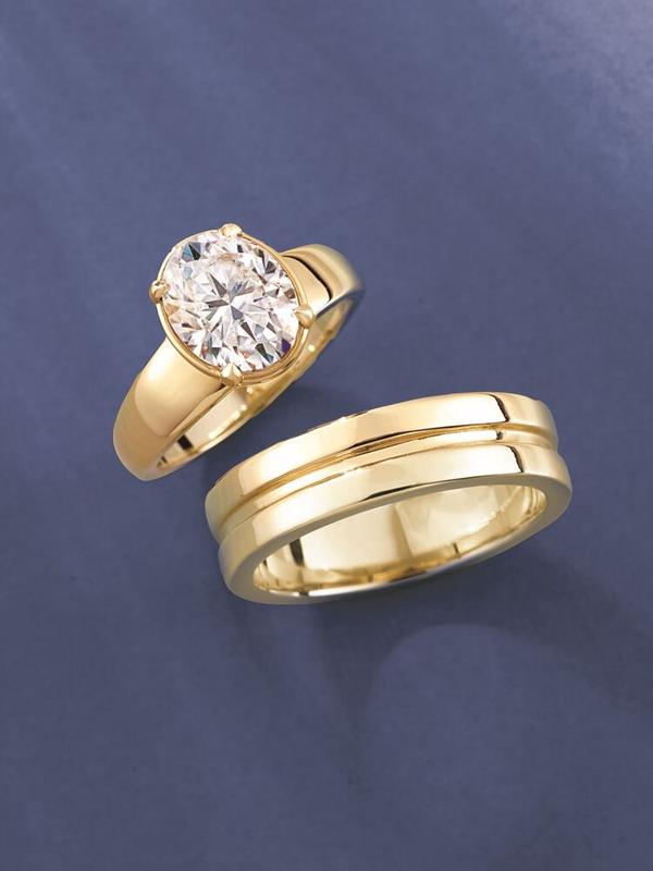 Oval bezel-set engagement ring with men's grooved wedding band