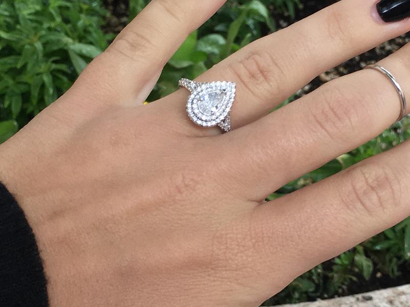 Pear-shaped diamond halo engagement ring worn on hand