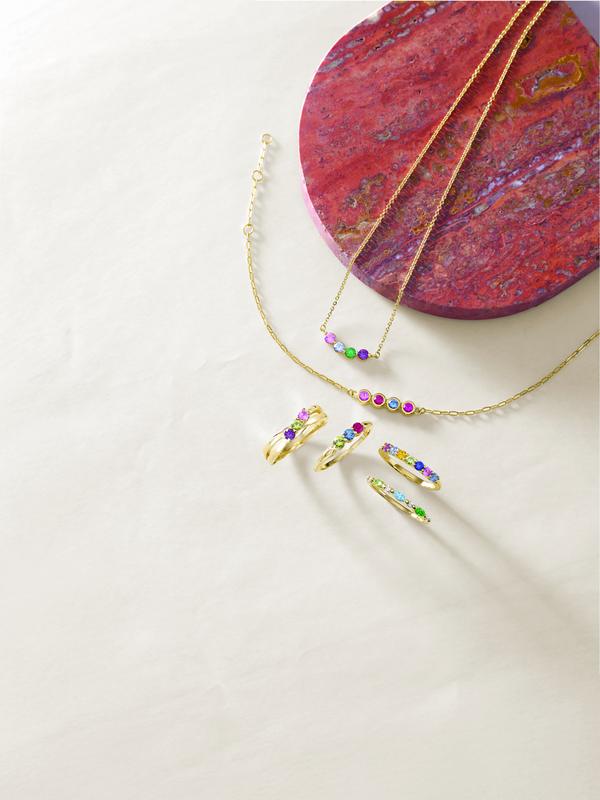 Colored gemstone rings and gold necklace flat lay
