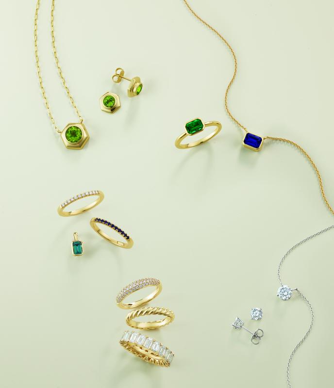 Green gemstone jewelry and gold stacking rings flat lay