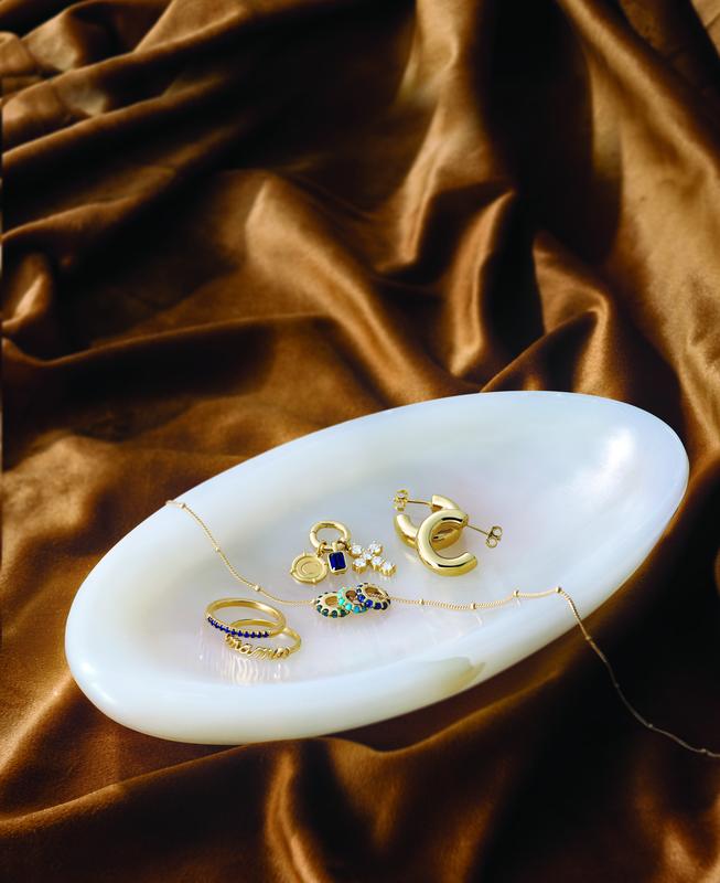 Gold charms and hoop earrings on a silk tray